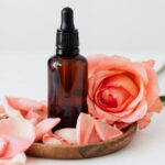 Fläschchen mit Massageöl mit Rose und Roseblättern