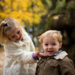 Mädchen und Junge Kleinkinder lächeln spielerisch im Freien Hintergrund herbstliche Stimmung